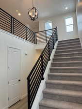 Stairs featuring hardwood / wood-style flooring and an inviting chandelier