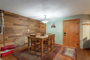 Dining area featuring wooden walls, dark wood-type flooring, and a textured ceiling