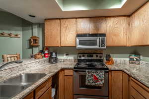 Kitchen featuring light stone countertops, sink, and stainless steel appliances