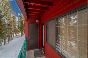 Snow covered property entrance featuring a balcony