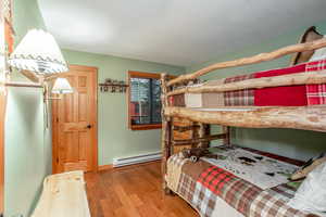 Bedroom featuring hardwood / wood-style flooring and a baseboard heating unit