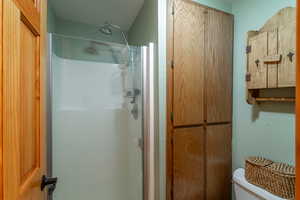 Bathroom with toilet, a shower, and a textured ceiling