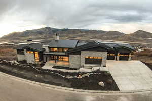 View of front facade featuring a standing seam roof, stone siding, a metal roof, driveway, and a mountain view