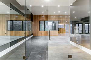 Home Gym with decrative wood trim, mirrors, rubber floors, european glass door and a drinking fountain.