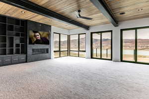 Living room featuring a premium fireplace, a mountain view, recessed lighting, ceiling fan, and a wood ceiling with exposed beams.