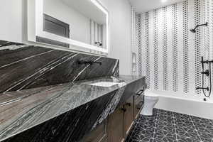 Geust Ensuite Bathroom featuring vanity, washtub / shower combination, and dark tile patterned flooring