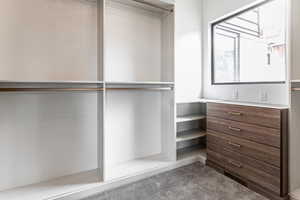 Primary bedroom closet - Walk in closet featuring, stacked washer and dryer and completly built out.