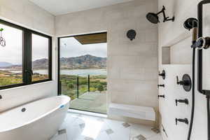 Primary Bathroom featuring double vanity, a chandelier, walk in shower, steam/wetroom, stand alone tub and a spacious closet with a stackable washer/dryer.