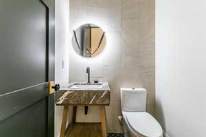 Common area powder room.  Half bathroom featuring tile walls and vanity