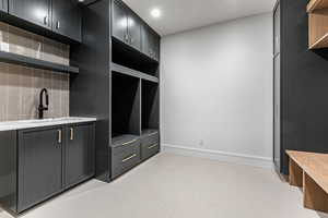Mudroom with baseboards and light floors, sink and washer/dryer.