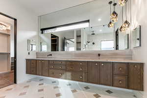 Primary Bathroom featuring double vanity, a chandelier, walk in shower, steam/wetroom, stand alone tub and a spacious closet with a stackable washer/dryer.