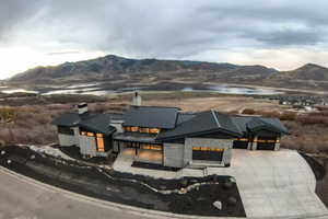 View of front of home featuring a chimney, a metal roof, a standing seam roof, stone siding, and concrete driveway