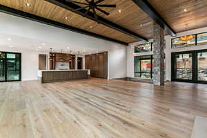 Living room with a mountain view, a fireplace, light wood finished floors, a wooden ceiling with exposed beams, and natural light