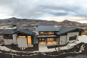Contemporary house with stone siding, a standing seam roof, and a mountain view