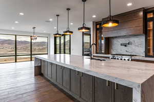 Kitchen with light stone countertops, hanging light fixtures, a mountain view, and recessed lighting