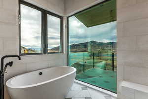 Primary wet-room with walk in shower, steamer, a freestanding bath, and a water and mountain view