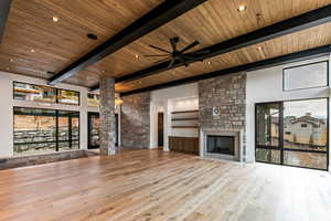 Living room with a mountain view, a fireplace, light wood finished floors, a wooden ceiling with exposed beams, and natural light