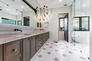 Primary Bathroom featuring double vanity, a chandelier, walk in shower, steam/wetroom, stand alone tub and a spacious closet with a stackable washer/dryer.