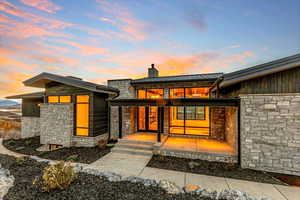 Front entry of house featuring stone siding, a standing seam roof, a chimney, and a metal roof