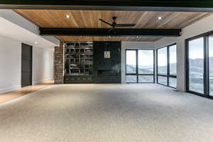 Living room featuring a premium fireplace, a mountain view, recessed lighting, ceiling fan, and a wood ceiling with exposed beams