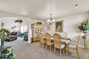 Carpeted dining space with a notable chandelier