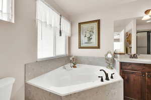 Bathroom with vanity, toilet, and tiled tub