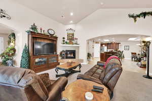 Carpeted living room with a tile fireplace, vaulted ceiling, and an inviting chandelier