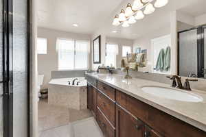 Full bathroom with tile patterned floors, a wealth of natural light, vanity, and separate shower and tub