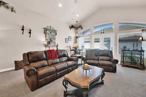 Carpeted living room with ceiling fan, french doors, and lofted ceiling