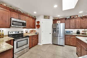 Kitchen with light stone countertops and appliances with stainless steel finishes