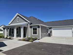 View of front of house featuring covered porch, central AC, and a garage