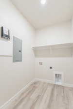 Washroom featuring electric dryer hookup, electric panel, hookup for a washing machine, and light hardwood / wood-style floors