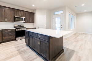 Kitchen featuring a center island, light hardwood / wood-style flooring, appliances with stainless steel finishes, and tasteful backsplash