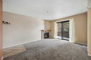 Unfurnished living room with a stone fireplace and light carpet