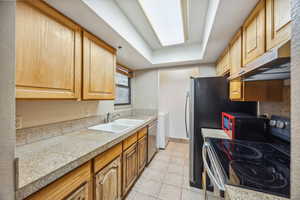 Kitchen featuring dishwasher, ventilation hood, a raised ceiling, range with electric cooktop, and sink