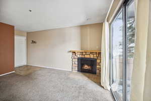 Unfurnished living room featuring a stone fireplace and light carpet