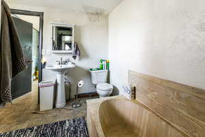 Bathroom featuring toilet, a tub, and sink