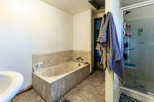 Bathroom with a textured ceiling and separate shower and tub