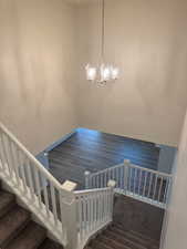 Staircase with hardwood / wood-style floors and an inviting chandelier