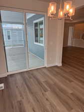 Unfurnished dining area featuring hardwood / wood-style floors and an inviting chandelier