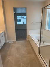 Bathroom featuring tile patterned flooring, vanity, and separate shower and tub