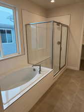 Bathroom featuring shower with separate bathtub and tile patterned floors