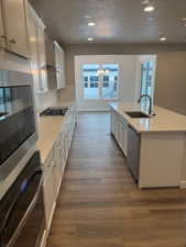 Kitchen featuring appliances with stainless steel finishes, sink, a center island with sink, dark hardwood / wood-style floors, and white cabinetry