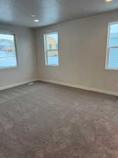 Carpeted empty room featuring a healthy amount of sunlight and a textured ceiling