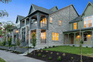 View of front facade featuring stone siding, a balcony, and a front yard