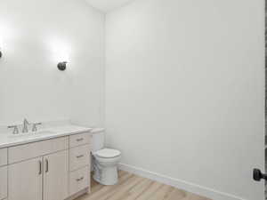 Bathroom with hardwood / wood-style floors, vanity, and toilet