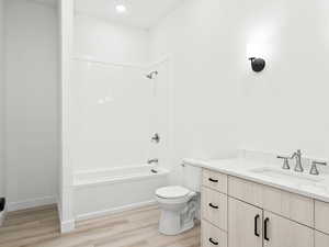 Full bathroom with shower / washtub combination, toilet, vanity, and hardwood / wood-style flooring