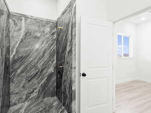 Bathroom featuring tiled shower and wood-type flooring