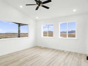 Unfurnished room with a mountain view, light hardwood / wood-style flooring, and ceiling fan