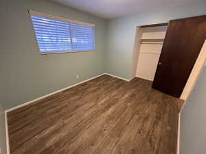 Unfurnished bedroom featuring dark hardwood / wood-style flooring and a closet